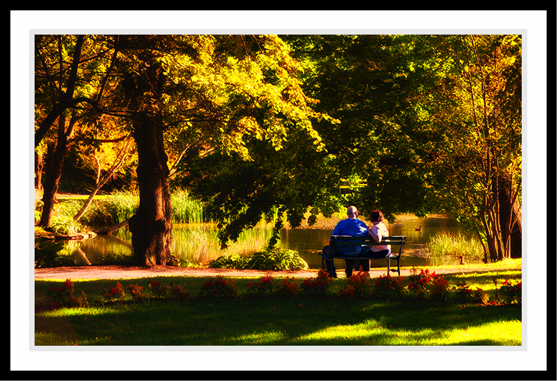 A couple sitting on a bench near the water.